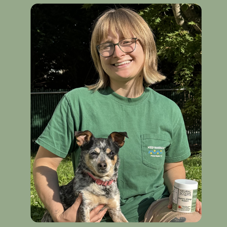 Customer holding Neural Scoops Daytime Allergy Support while sitting outdoors with a dog.